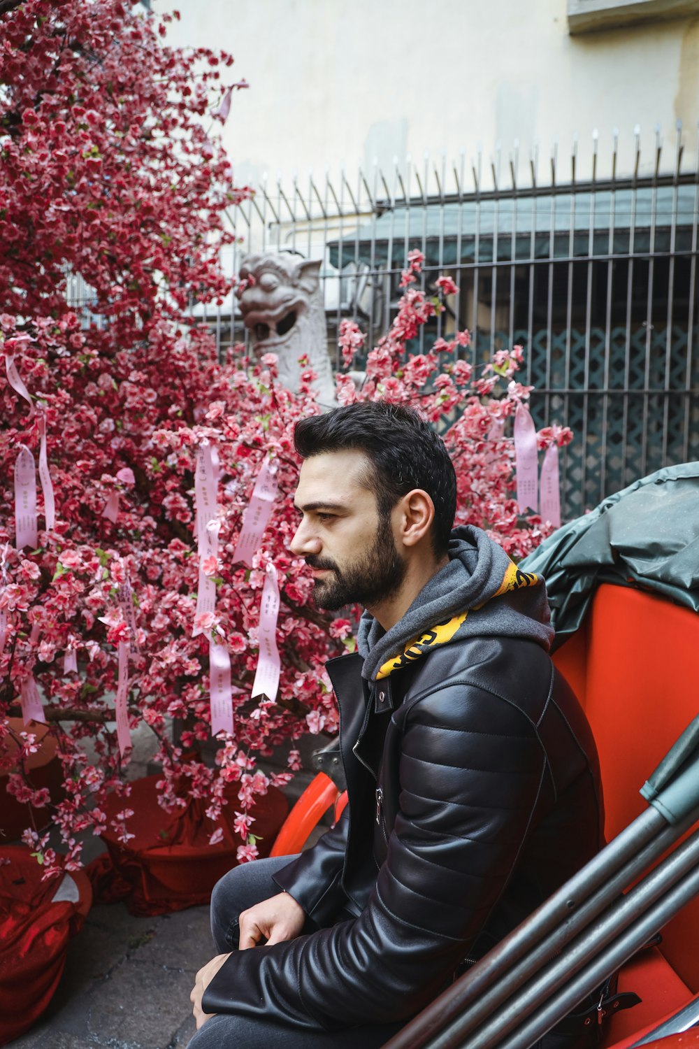 man in black and yellow jacket standing near red flowers during daytime