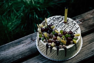 Close-up of a beautifully decorated chilled cake with olive green accents on a rustic wooden table.