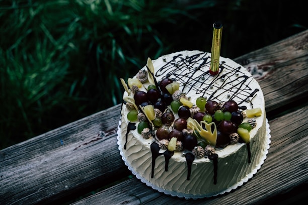 Close-up of a beautifully decorated chilled cake with olive green accents on a rustic wooden table.
