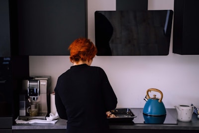 man in black shirt standing in front of kitchen sink