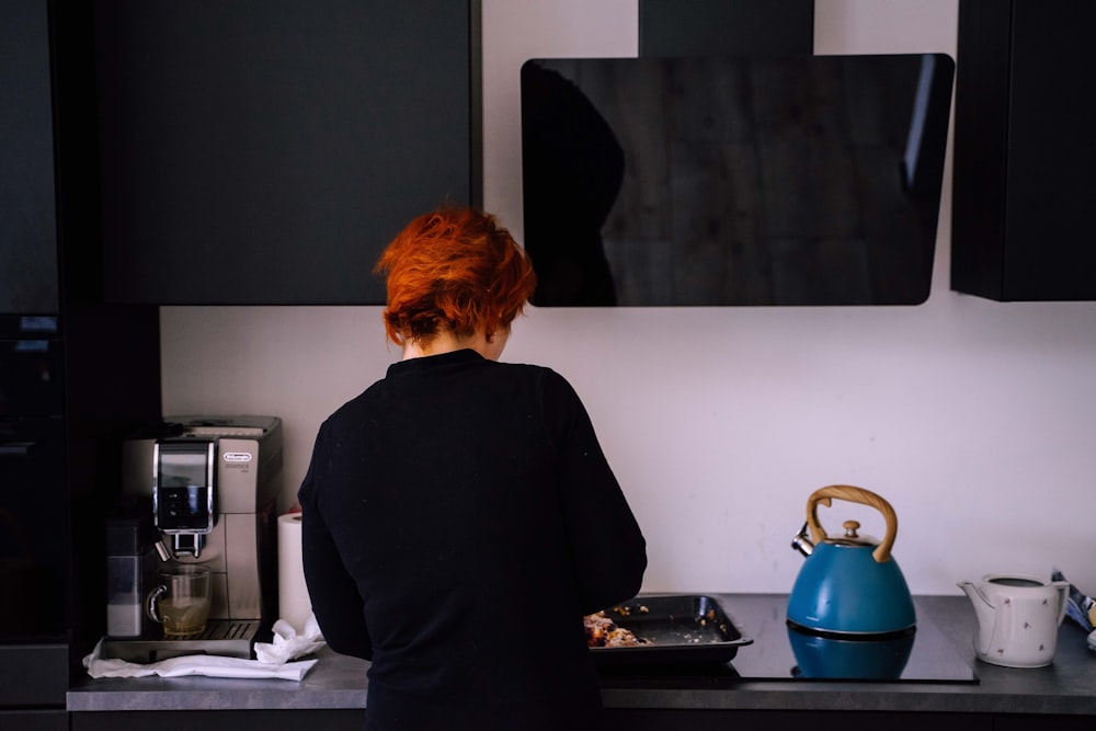 man in black shirt standing in front of kitchen sink