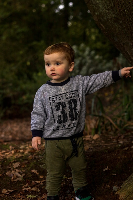 boy in gray sweater standing on brown soil in Hamilton New Zealand