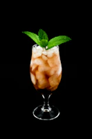 A refreshing iced coffee in a tall glass with condensation, garnished with a sprig of mint.