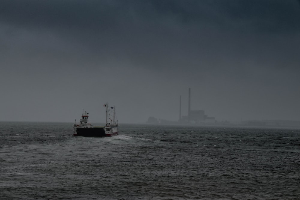 red and black boat on sea under white clouds during daytime