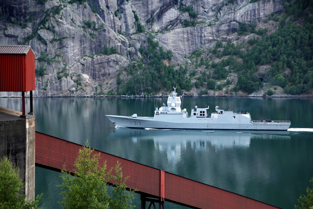 weißes Boot tagsüber auf einem Gewässer in der Nähe der Brücke