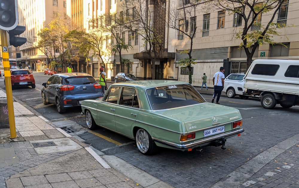 green sedan parked on sidewalk during daytime