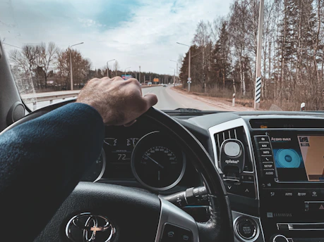 A professional driver confidently handling a modern vehicle on a clear road.