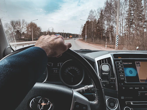 A professional driver confidently handling a modern family car on a clear road.