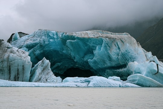 white and blue ice on white sand during daytime in Tasman Glacier New Zealand