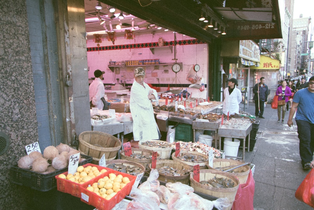 man in white dress shirt standing in front of fruit stand