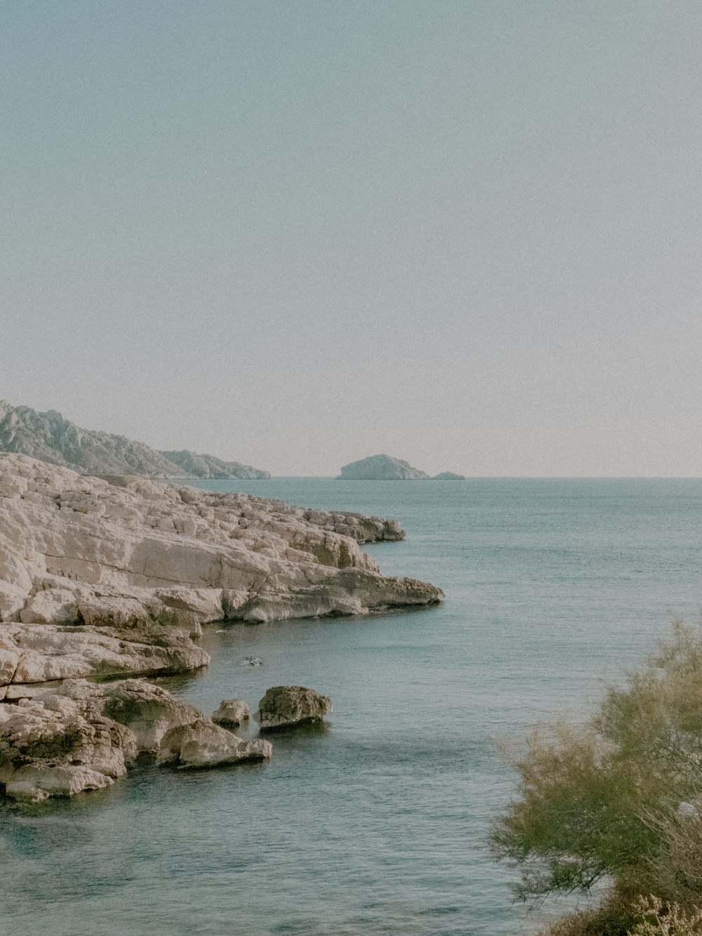 brown rocky mountain beside blue sea under blue sky during daytime