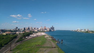 people walking on green grass field near body of water during daytime michigan google meet background