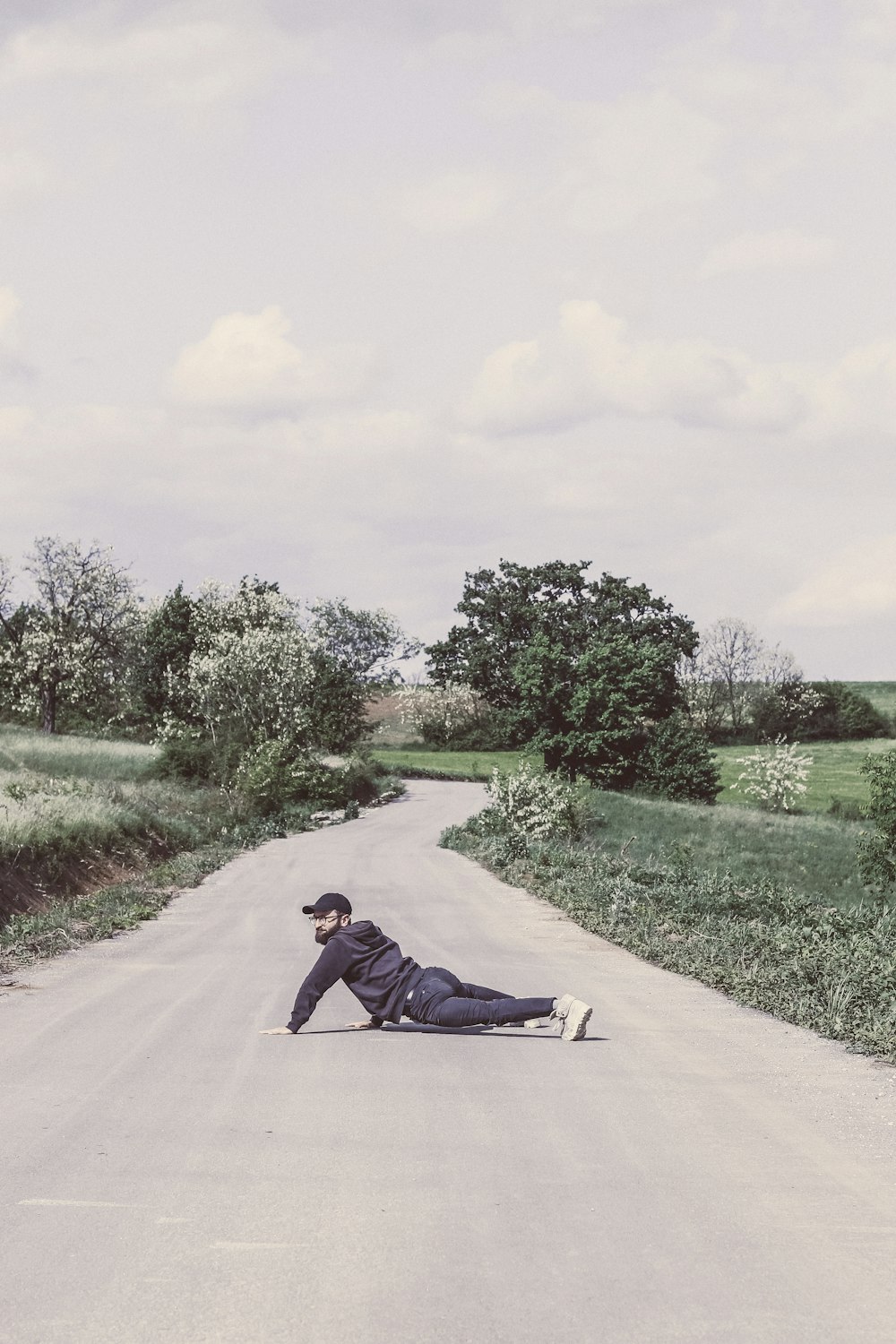 man in black jacket lying on gray concrete road during daytime