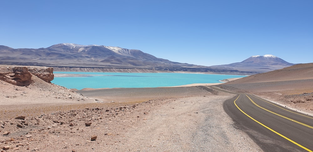 blue body of water near mountain under blue sky during daytime