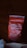 A red bag of coffee labeled 'NECESSARY COFFEE' with additional text stating 'STRONG PARTNERS MAKE RICH COFFEE' and 'ETHIOPIA' on it. The bag appears slightly crumpled and is set against a dark wooden background.