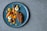 A beautifully arranged gourmet dish on a blue ceramic plate, featuring slices of roast meat and an artistic assortment of colorful vegetables including carrots, onions, and cherries. Small dots of vibrant orange puree add a touch of elegance.