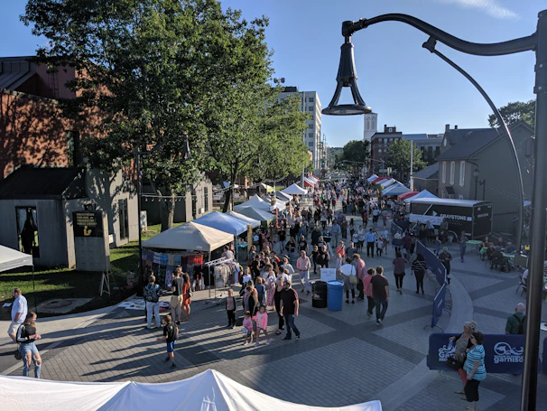 A bustling outdoor market scene with colorful stalls and happy shoppers enjoying a sunny Sunday morning.