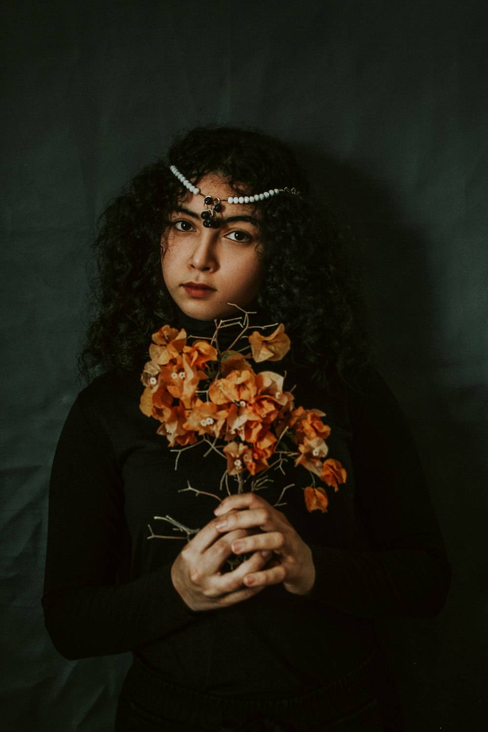 woman in black long sleeve shirt holding orange flowers