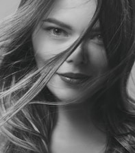 Close-up portrait of a confident woman sharing her story in a stylish, minimal setting.