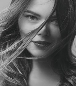 Close-up portrait of a confident woman sharing her story in a stylish, minimal setting.