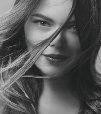 Close-up of a confident woman smiling with a playful, inviting gaze.