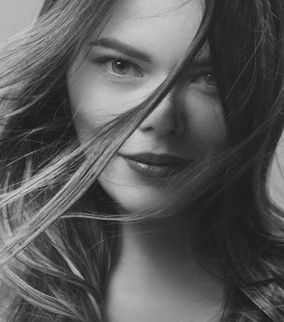 Close-up of a confident woman smiling with a playful, inviting gaze.