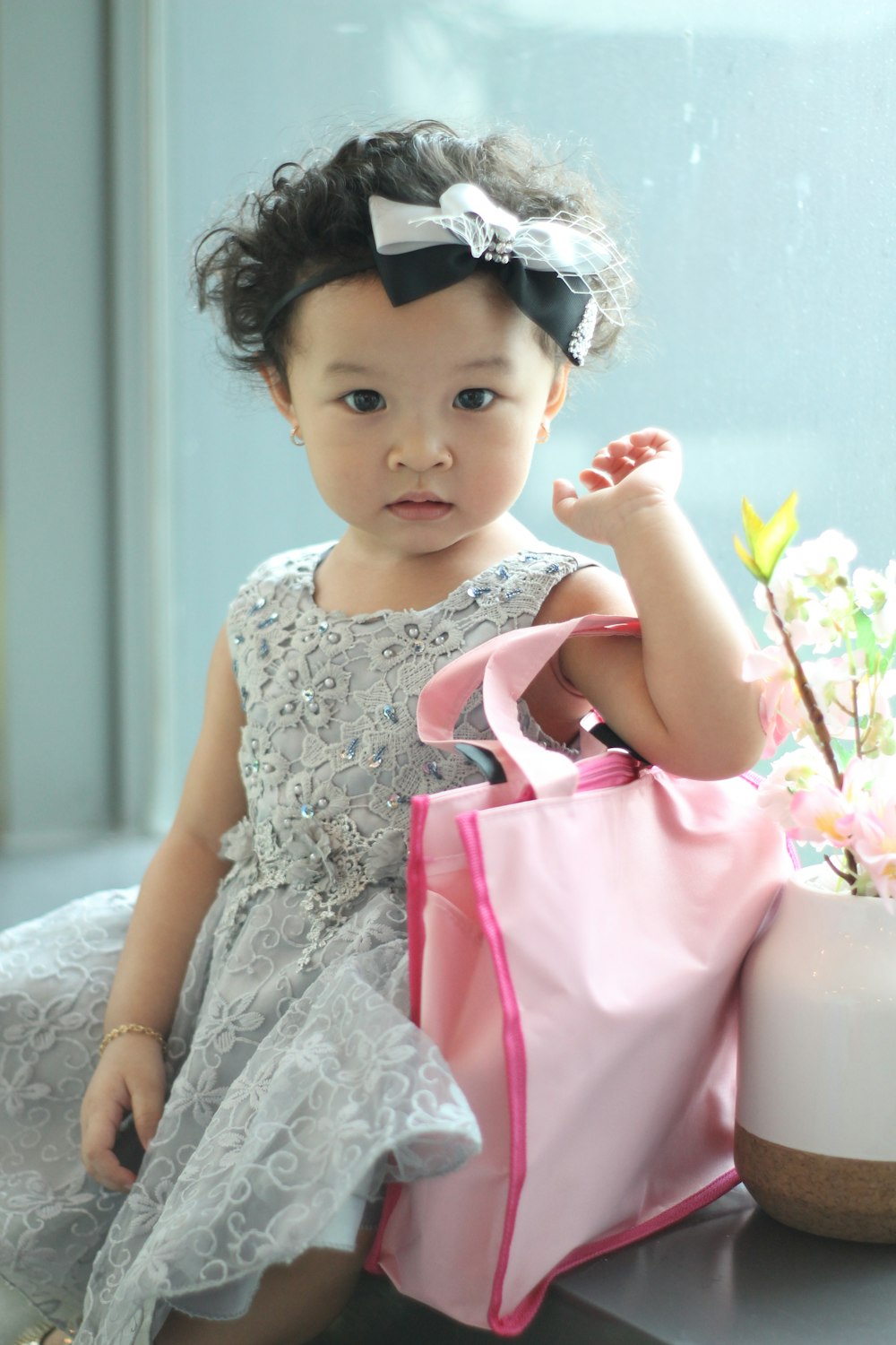 girl in white floral sleeveless dress sitting on white textile