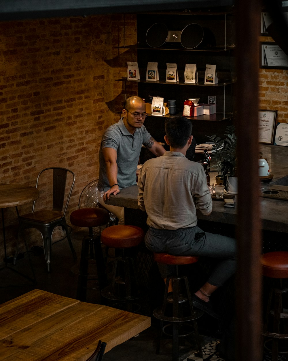 man in gray long sleeve shirt sitting on brown wooden seat