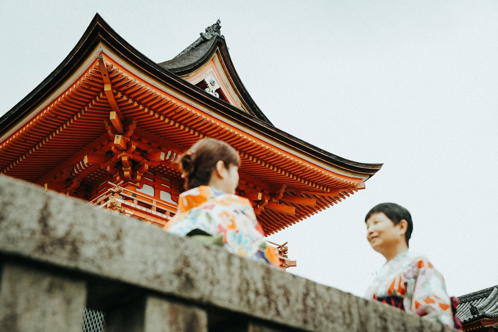 woman in white and red floral dress standing near red and brown temple during daytime