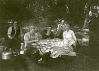 A group of friends enjoying a picnic, dressed in trendy outdoor wear.