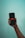 A hand holding a smartphone with the Netflix logo displayed on the screen against a light blue background.