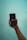 A hand holding a smartphone with the Netflix logo displayed on the screen against a light blue background.