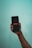 A hand holding a smartphone with the Netflix logo displayed on the screen against a light blue background.