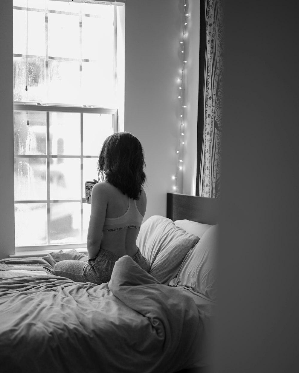 woman in white tank top sitting on bed