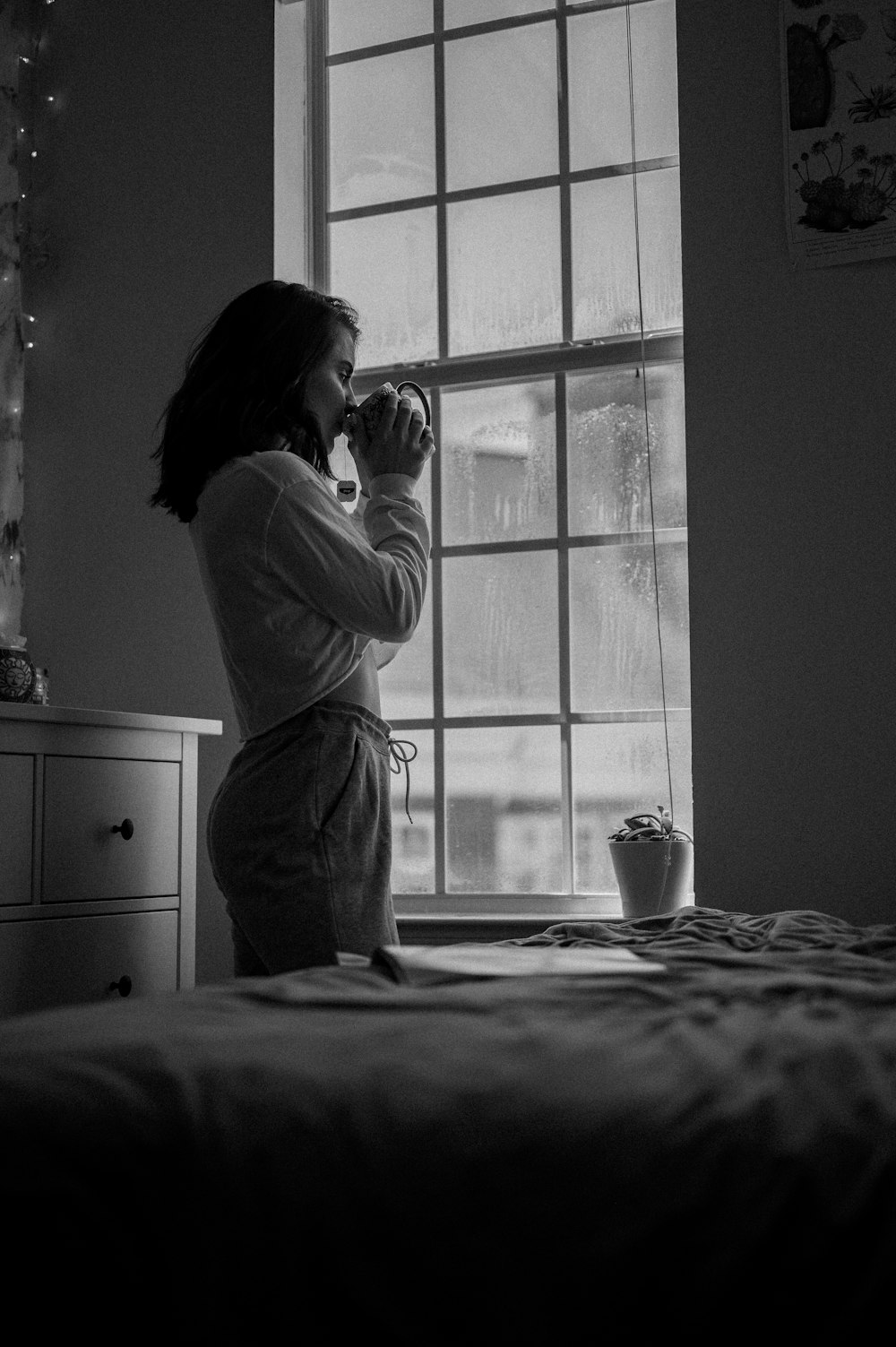 woman in white long sleeve shirt standing near window