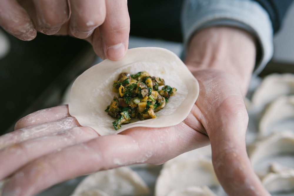 person holding white ceramic plate with green vegetable dish