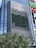 A tall building with a large electronic billboard displaying a video game screen, featuring a maze-like pattern and a score and timer at the top. The building is named 'MAGNET' and there are trees in the foreground.