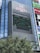 A tall building with a large electronic billboard displaying a video game screen, featuring a maze-like pattern and a score and timer at the top. The building is named 'MAGNET' and there are trees in the foreground.
