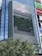 A tall building with a large electronic billboard displaying a video game screen, featuring a maze-like pattern and a score and timer at the top. The building is named 'MAGNET' and there are trees in the foreground.