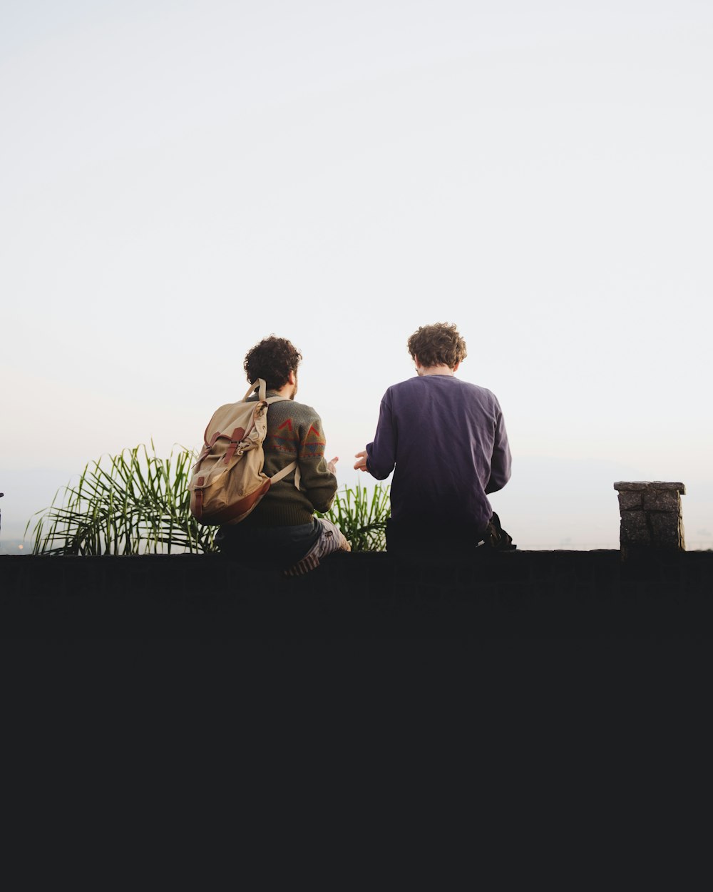 man and woman sitting on brown wooden bench during daytime