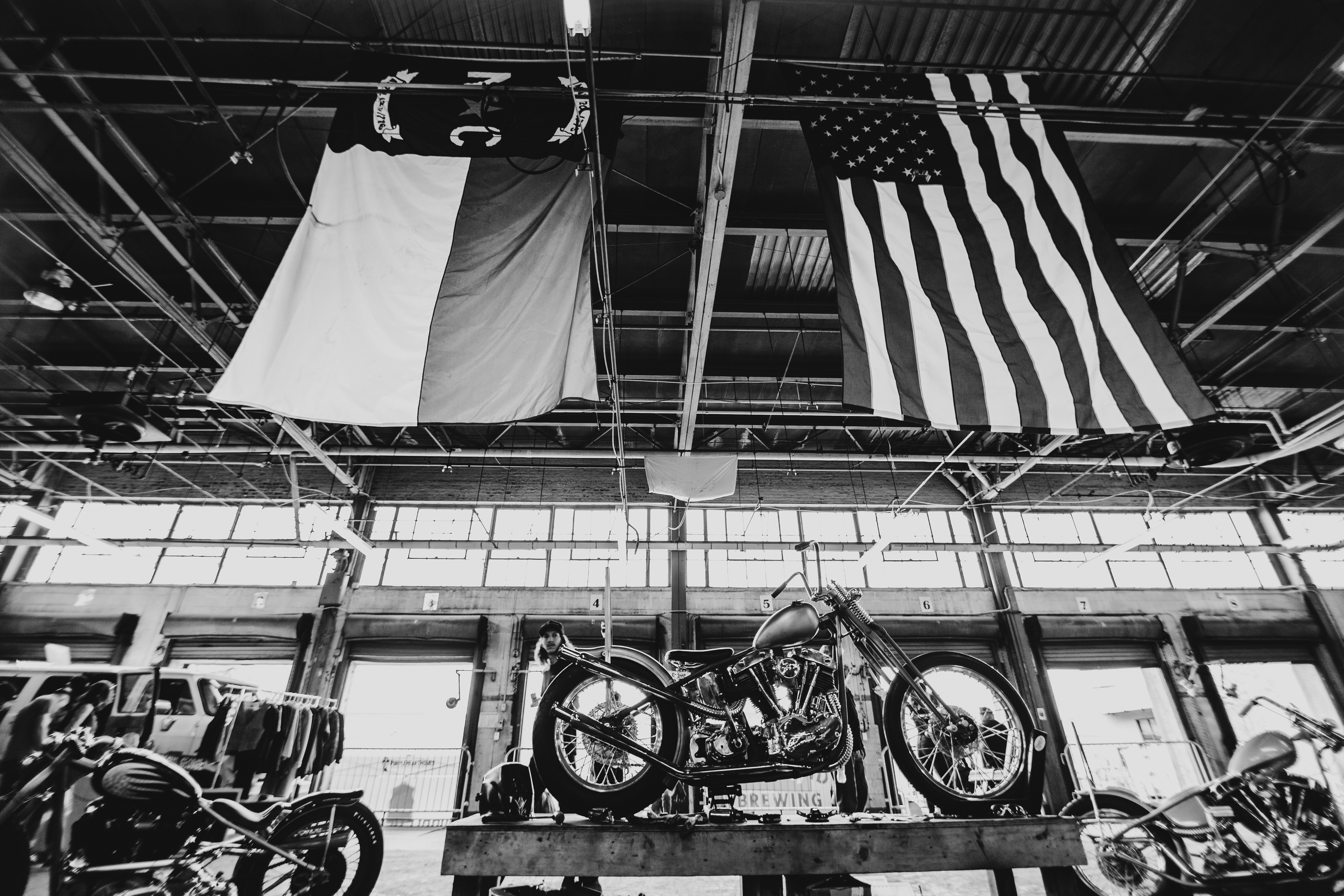 grayscale photo of a motorcycle and a flag of us a on a pole