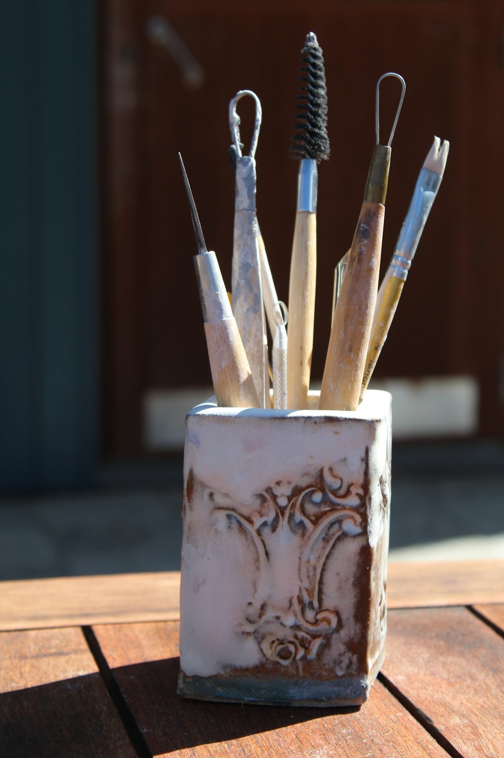 white and brown ceramic mug with paint brushes