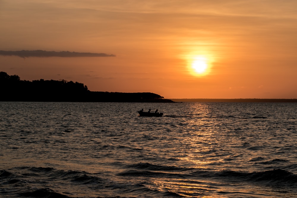 silhouette of boat on sea during sunset