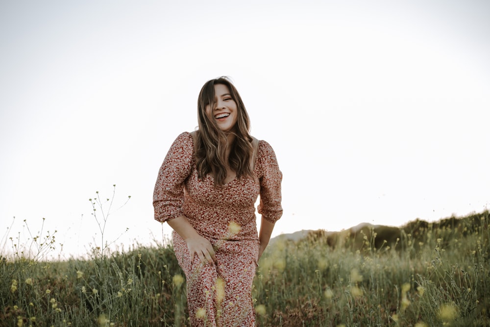 woman in red and white floral dress standing on green grass field during daytime