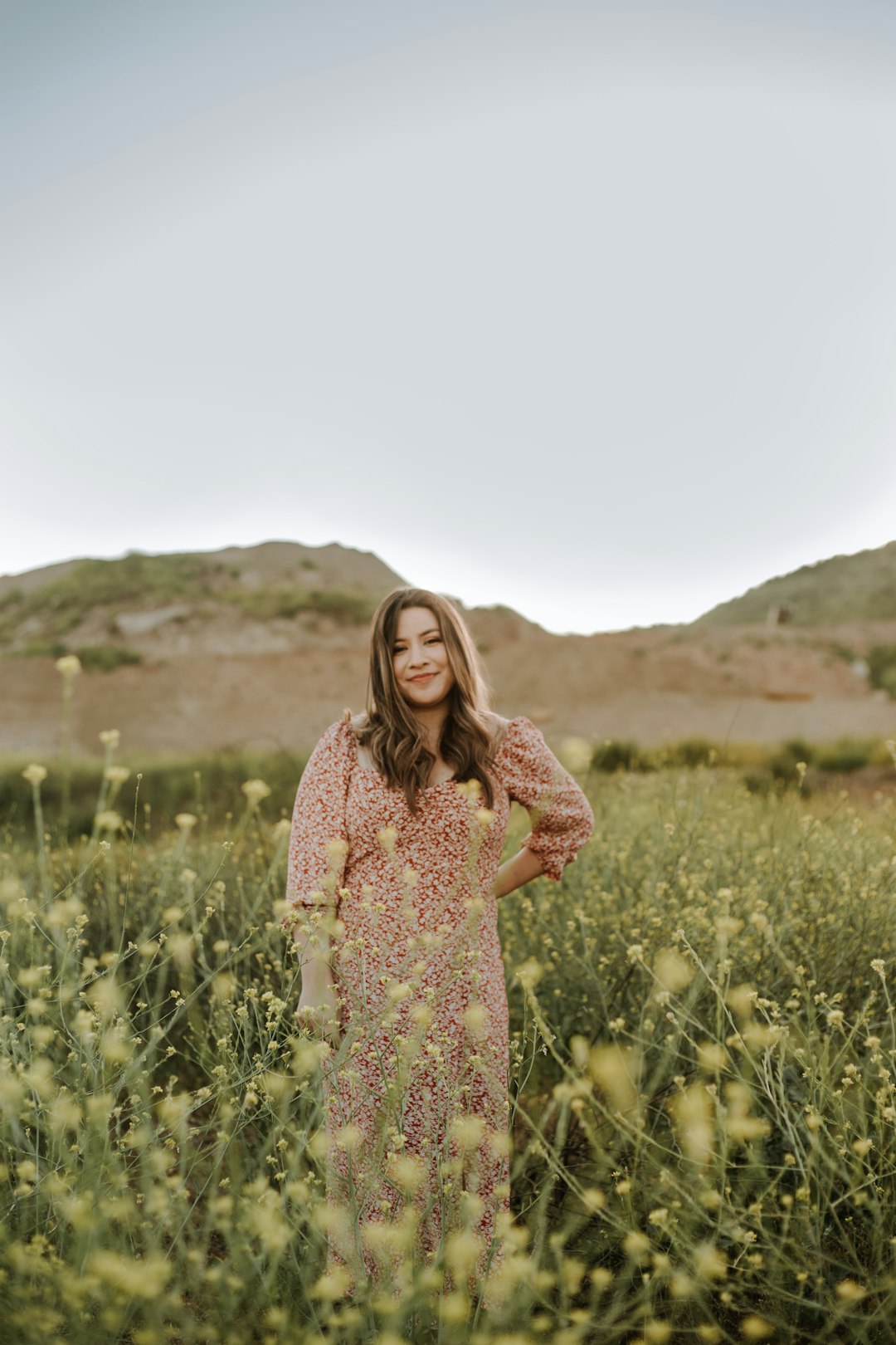 woman in brown and white floral dress standing on green grass field during daytime