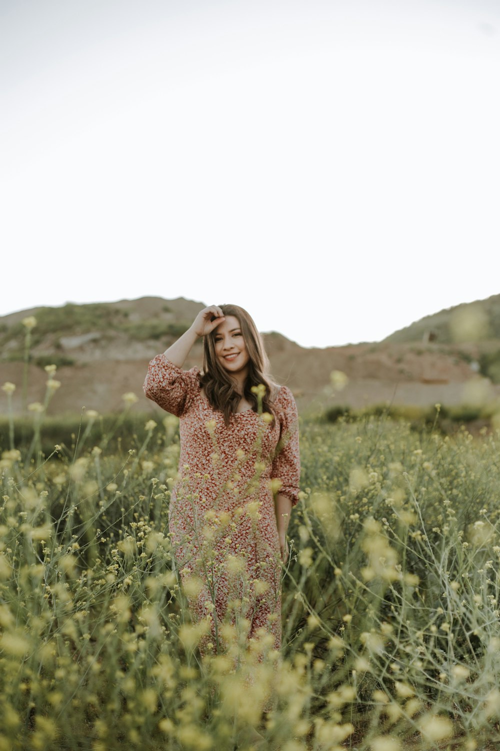 woman in red and white floral dress standing on green grass field during daytime