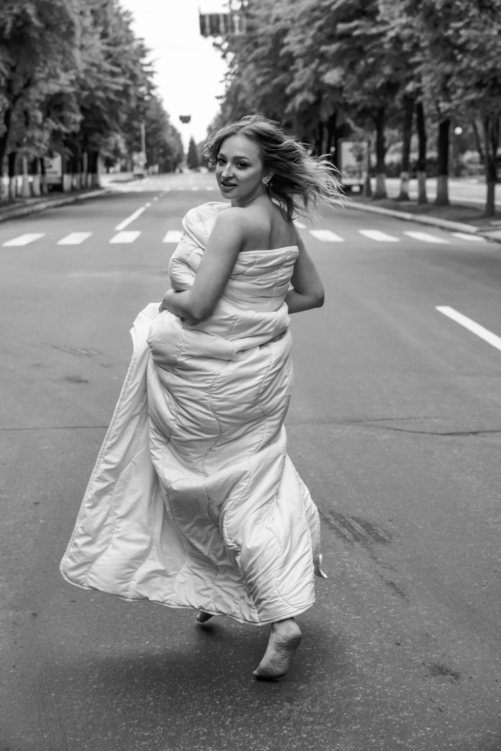 grayscale photo of woman in dress standing on road