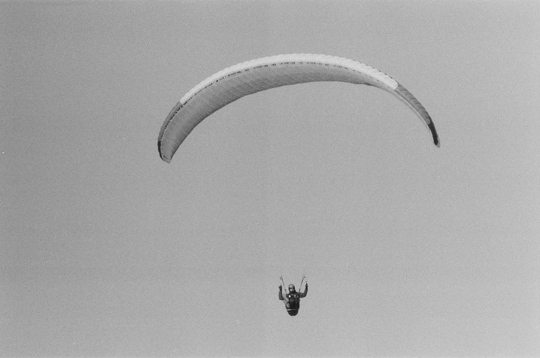 grayscale photo of person riding on parachute