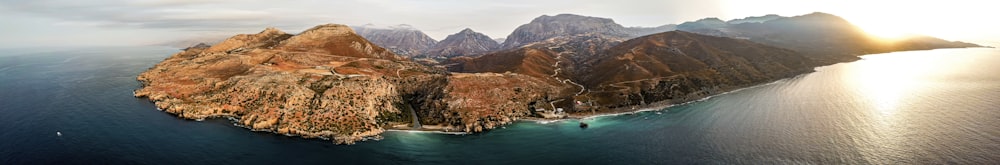 Montañas marrones y verdes junto al mar azul durante el día