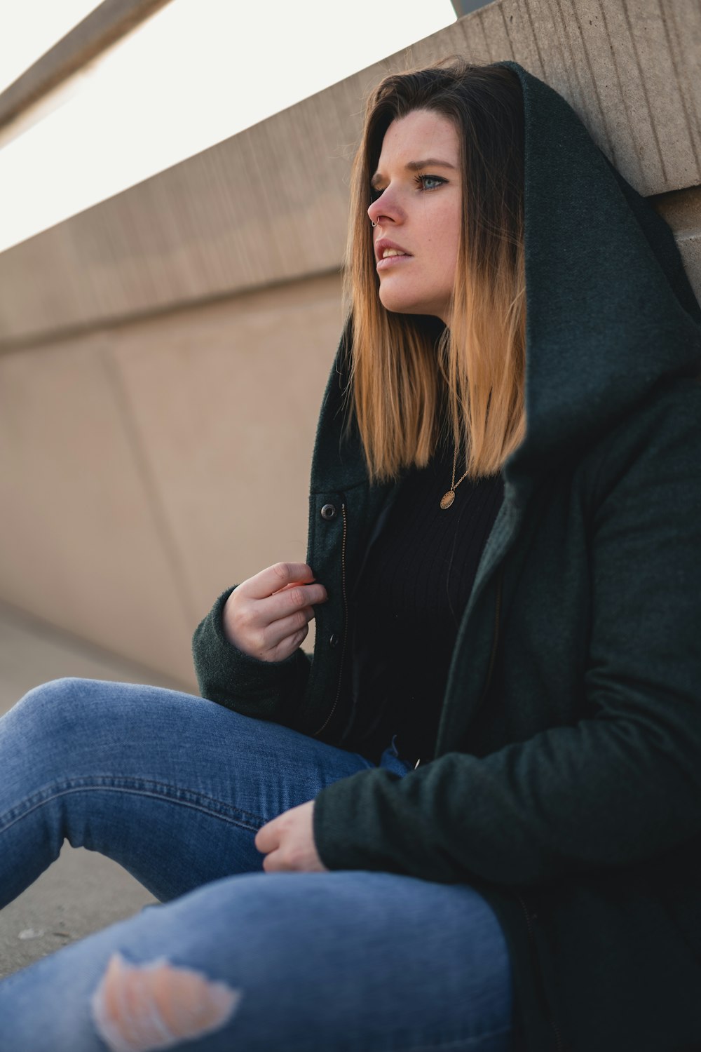 Femme en veste noire et jean bleu assise sur les escaliers